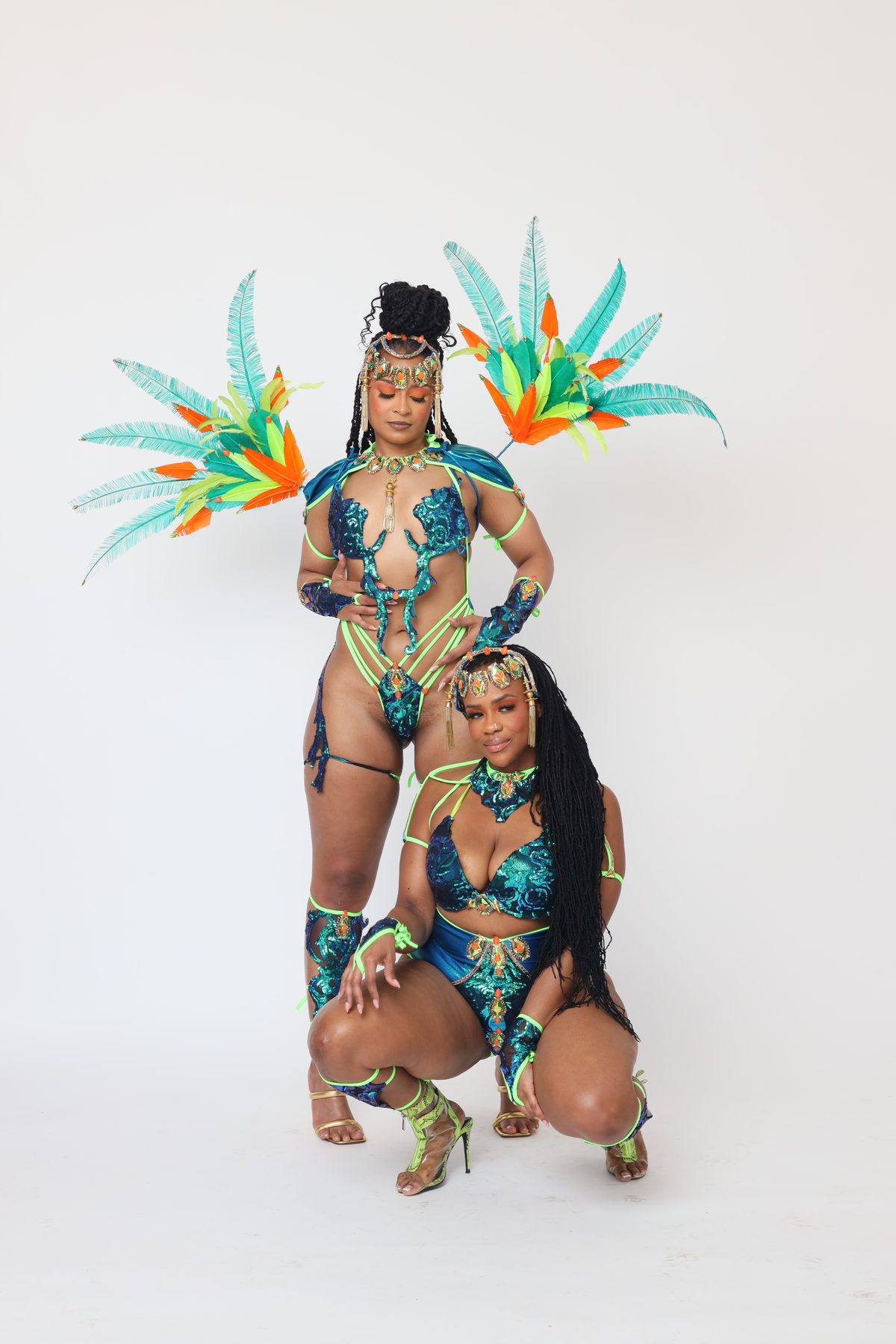 Pretty Mas carnival commission — two models in matched teal sequin pieces with coral feather accents